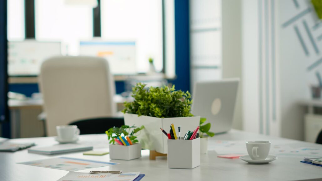 Karriere 4 Heller Besprechungstisch in einem modernen Büro mit Pflanzen, Stiften, Kaffeetassen und Dokumenten.